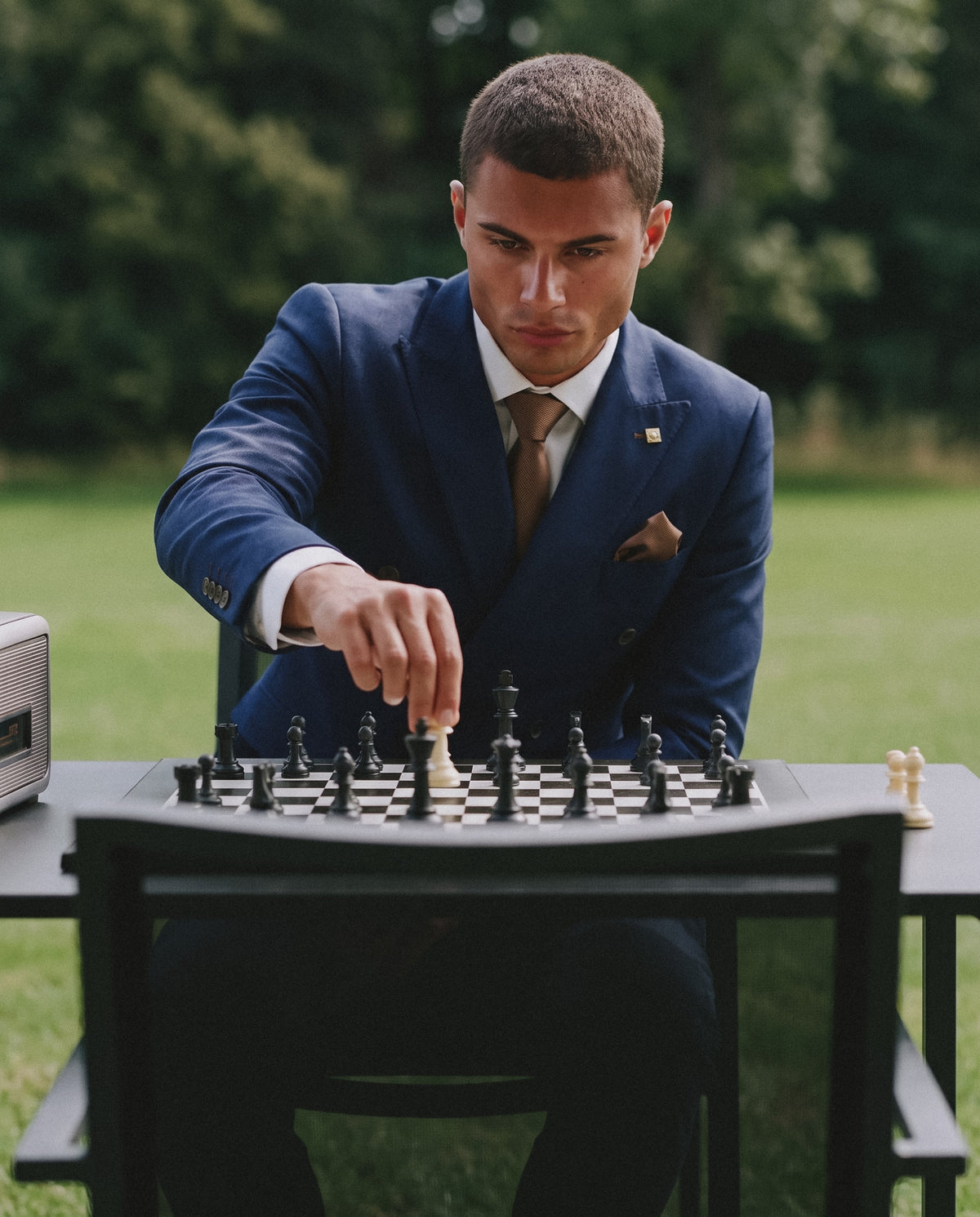 Man in a navy double breasted suit making a move on a chessboard